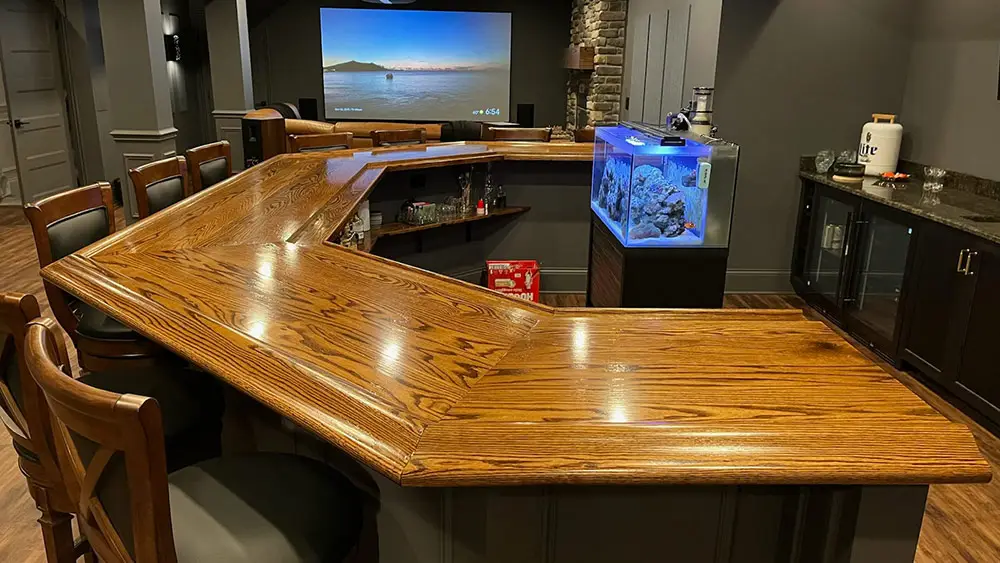 Home bar area with dark cabinets, a fish tank, with a wooden Bar Top and Bar Rail from Hardwoods Incorporated