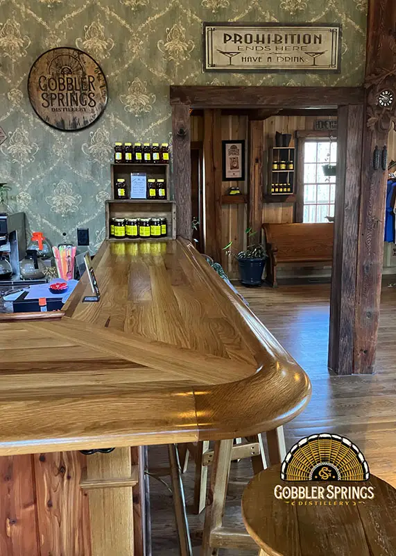 Partial view of wooden bar made from light-colored wood and matching bar rail from Hardwoods Incorporated.