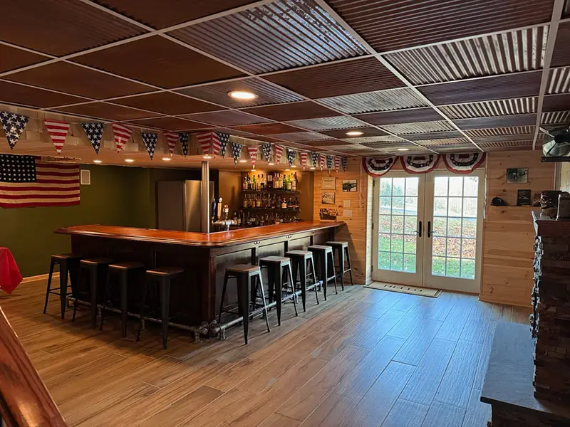 L-shaped bar made from dark colored wood with matching bar rail provided by Hardwoods Incorporated.