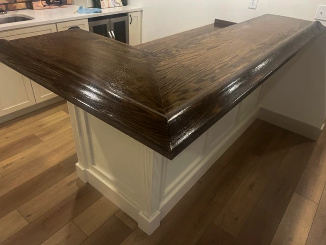 Small home bar with white cabinetry and dark BR475 Bar Rail Molding from Hardwoods Incorporated